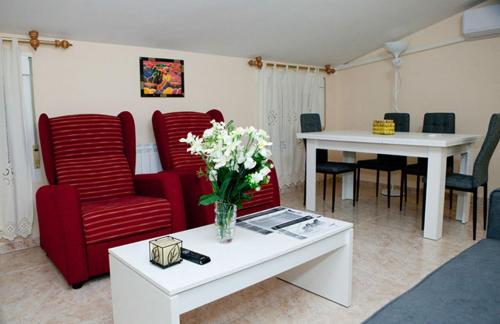 哈兰迪雅·德·拉·维尔Apartamento La Relojera 1的客厅配有红色椅子和鲜花桌