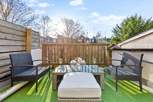 伦敦Balcony Blue Theme 1 Bedroom Central London Luxury Flat Near Hyde Park! Accommodates up to 6! Double Sofa Bed and Next to Station!的天井配有两把椅子和一张桌子,位于草地上