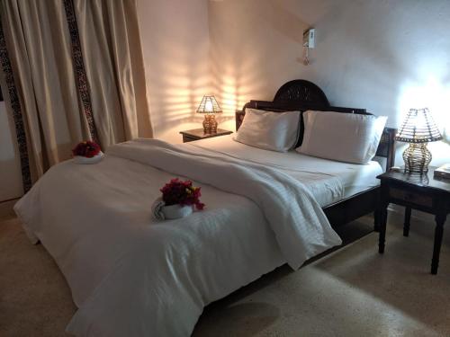 马林迪Karibuni Villa - Malindi beach view property的一间卧室配有一张白色大床,床上有鲜花