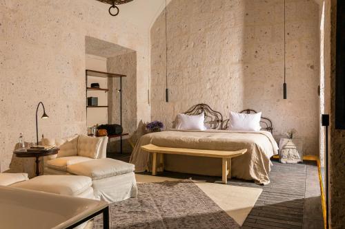 阿雷基帕CIRQA - Relais & Châteaux的一间卧室配有一张床、一张桌子和一张沙发