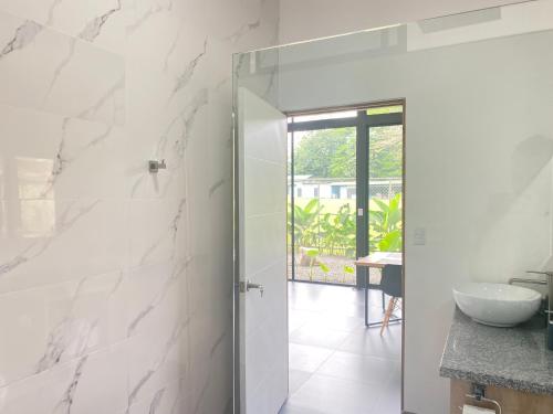 福尔图纳Toucan home的浴室设有白色大理石墙壁和玻璃门
