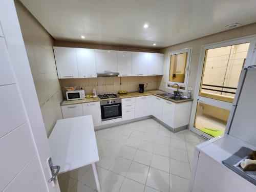拉古莱特Gouletteparadis的厨房配有白色橱柜和白色瓷砖地板。