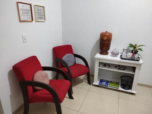Genuino SampaioQuarto confortável em Est Velha的一间设有两张红色椅子和一张桌子的房间