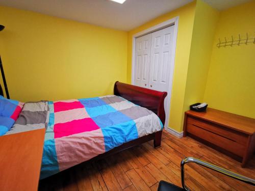 多伦多one queen-sized bed convenient location的一间卧室配有一张色彩缤纷的床,铺有木地板。