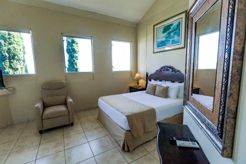 马那瓜Los Altos Apartments & Studios的一间卧室配有一张床、一把椅子和镜子