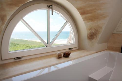 兰图姆Söl'ring Hof的带浴缸和大窗户的浴室内的拱形窗户