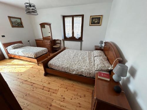 Bagnolo PiemonteCasa Salada的一间卧室配有两张床、一个梳妆台和镜子