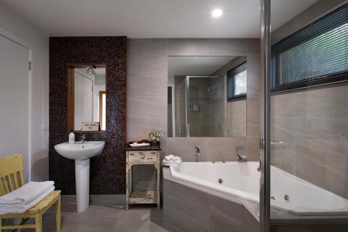 赫本温泉阿洛菲度假屋的浴室配有盥洗盆、浴缸和盥洗盆