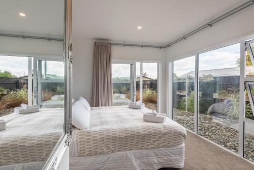 罗托鲁瓦Lakeside Gem的一间卧室设有床铺和大型玻璃窗