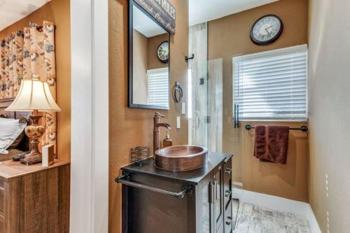 沃思堡Stockyards! Less than 3 mins-Sleeps 8 -Gable House的浴室设有水槽和墙上的带时钟的淋浴。