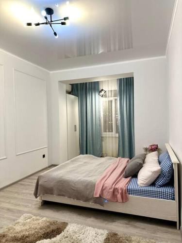 阿克套Жилой комплекс Махаббат的一间卧室配有一张带蓝色窗帘的大床