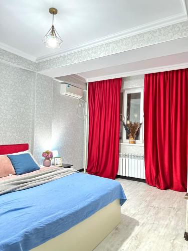 阿克套ЖК Тыныштык的一间带红色窗帘和床的卧室