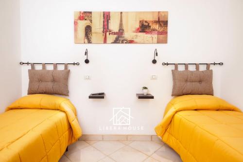 圣萨尔沃LIBERA HOUSE - Sweet Apartments的配有黄色床单的客房内的两张床