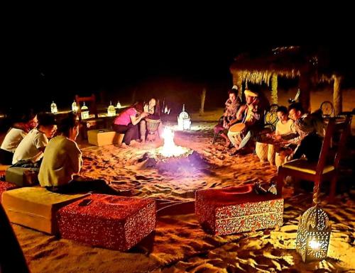 梅尔祖卡Sahara Safari Camp的一群人晚上坐在火坑周围