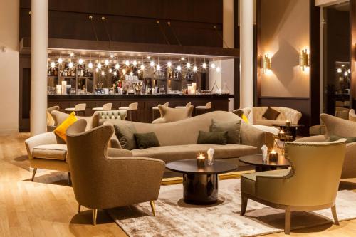 勒布尔热AC Hotel by Marriott Paris Le Bourget Airport的一个带沙发和桌子的大堂和一间酒吧