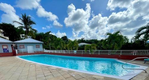 拉特里尼泰La Caravelle - Agréable studio vue sur mer avec piscine的棕榈树屋前的游泳池