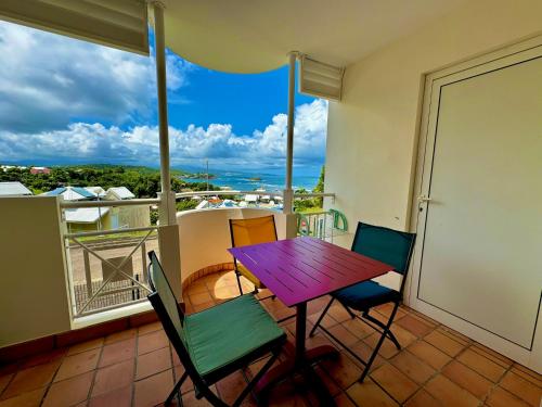 拉特里尼泰La Caravelle - Agréable studio vue sur mer avec piscine的美景阳台配有紫色的桌椅