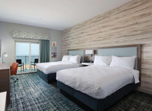 马尼斯蒂Hampton Inn & Suites Manistee, Mi的酒店客房设有两张床和一个阳台。