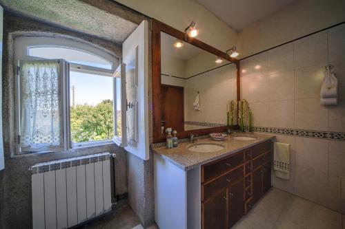 维亚纳堡Casa Praia e Campo的一间带水槽和镜子的浴室以及窗户。