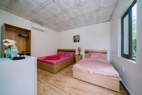 Hang SuốiWindy Garden Hostel的卧室内的两张床,配有粉红色的床单