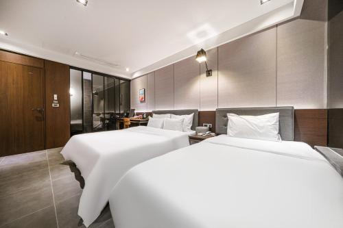 釜山Brown Dot Hotel Busan Station的配有白色床单的酒店客房内的两张床