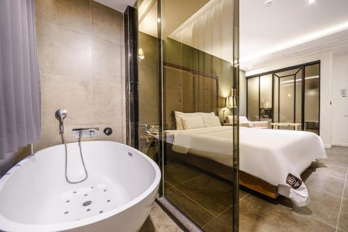 釜山Brown Dot Hotel Busan Station的卧室旁的浴室设有床和浴缸