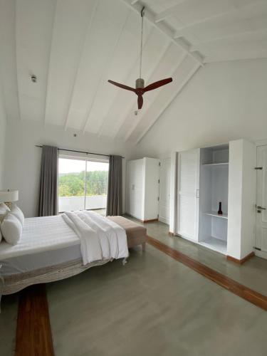 哈普特莱Benito Bungalow by The Serendipity Collection的白色卧室配有床和吊扇