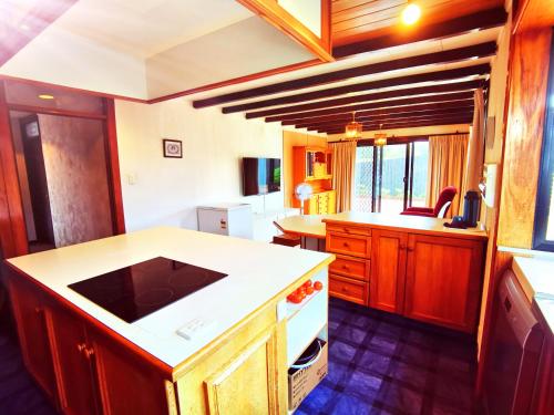 旺阿雷Denby Golf House Tikipunga的厨房配有木制橱柜和白色台面