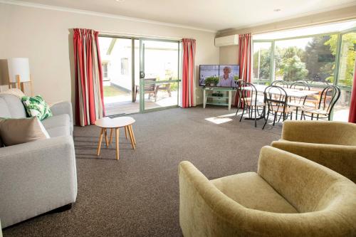 纳尔逊Tāhuna Beach Holiday Park的客厅配有沙发、椅子和桌子