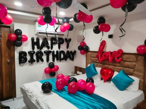 艾哈迈达巴德Hotel Palak Palacce的一间卧室,配有一张带气球的床和一个快乐的生日标志