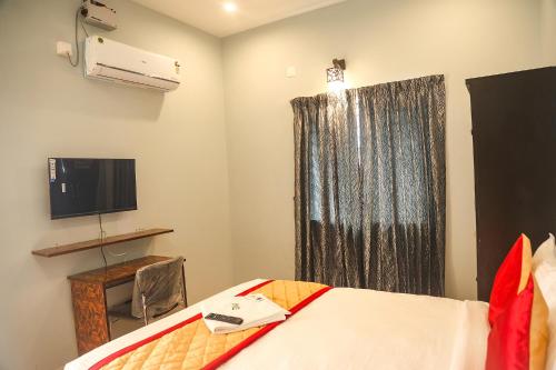 钦奈FabHotel Home Tree Service Apartment Kolathur的一间卧室设有一张床、一台电视和一个窗口。