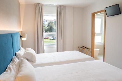 圣地亚哥－德孔波斯特拉Hotel Parking Miradoiro de Belvís的酒店客房设有两张床和窗户。