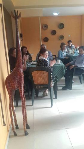 RukungiriHeritage Hotel Rukungiri的一群人坐在桌子上,拿着假长颈鹿