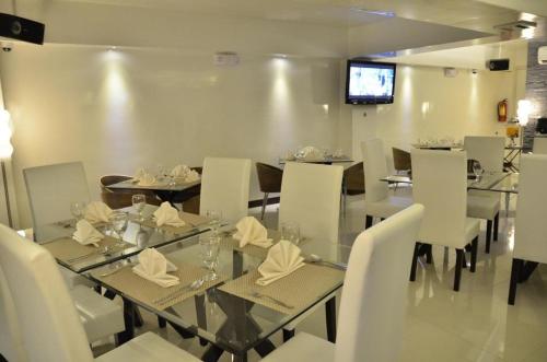 苏里高The Grande Suites的一间设有玻璃桌和白色椅子的用餐室