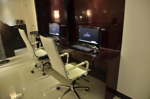 苏里高The Grande Suites的办公室,配有三把椅子和一张桌子及电脑