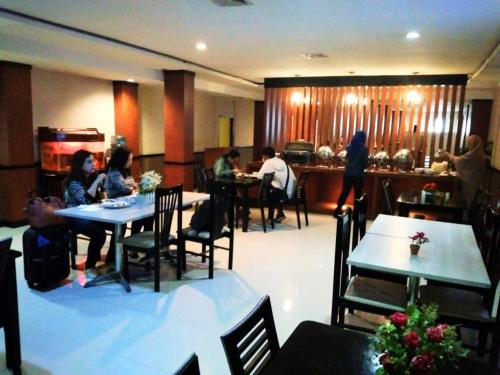 北干巴鲁Hotel Parma Pekanbaru的一群坐在餐厅桌子上的人