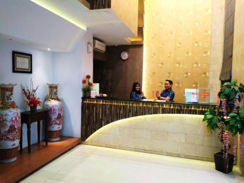 北干巴鲁Hotel Parma Pekanbaru的两人坐在餐厅柜台