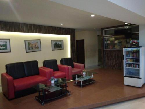 北干巴鲁Hotel Parma Pekanbaru的客厅配有红色椅子和书架