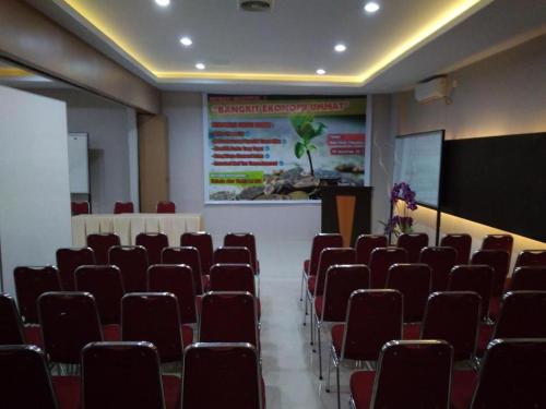 北干巴鲁Hotel Parma Pekanbaru的一个带红色椅子和屏幕的讲座大厅