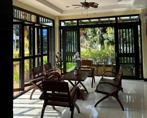 南府Ponburi Hotel的用餐室设有椅子、桌子和窗户