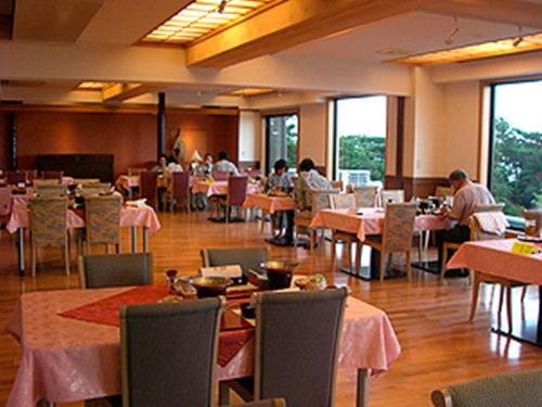 雾岛市Kirishima Onsen Ryokojin Sanso的一间设有桌子的餐厅,有坐在桌子上的人