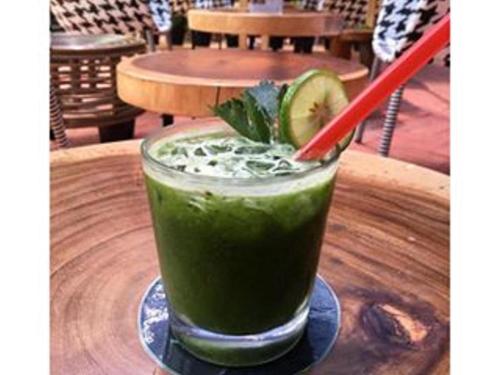 雅加达Couleur Hotel Cengkareng的木桌边的红草绿色饮料