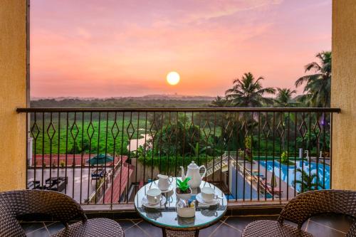 坎多林Golden Tulip Candolim, Goa的阳台配有桌椅,享有日落美景。