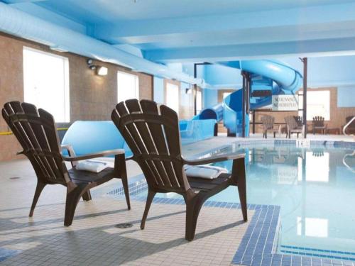 弗登Comfort Inn & Suites的游泳池畔的两把椅子和一张桌子