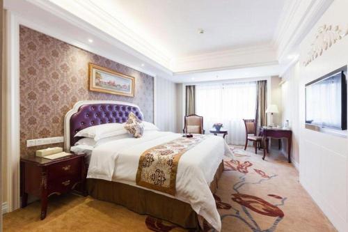 南宁Vienna Intenational Hotel Nanning Zoo Branch的一间卧室配有一张大床和紫色床头板