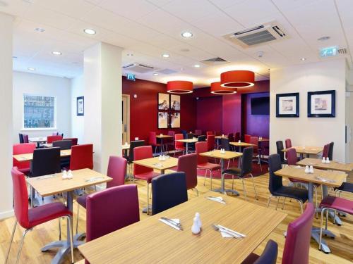格拉斯哥Travelodge Glasgow Queen Street的餐厅设有木桌和红色椅子