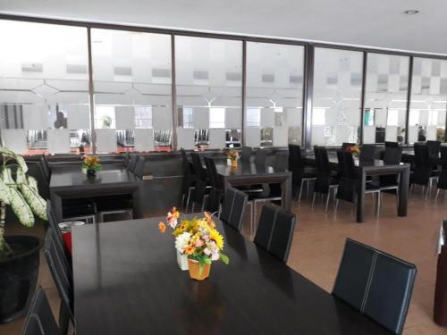 KlapalimaIma hotel的一间会议室,里面摆放着黑色的桌子和椅子,鲜花盛开