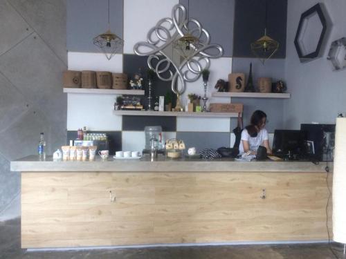 万隆The Batik Bed And Coffee Bandung的坐在咖啡店柜台的女人