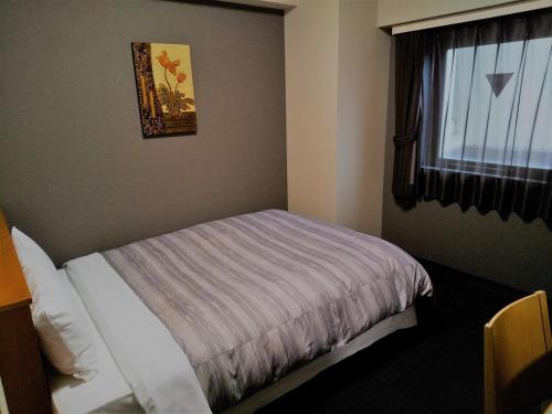 秋田格兰蒂亚路线秋田Spa度假经济型酒店的一间小卧室,配有床和窗户
