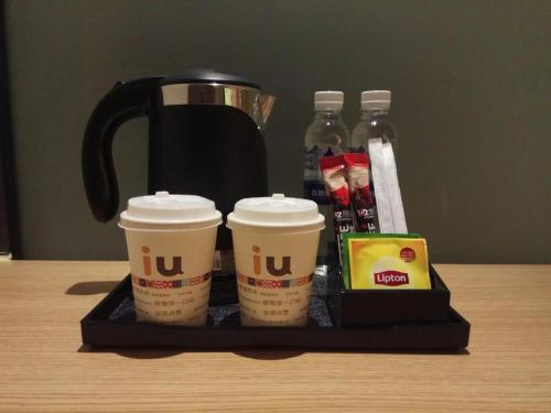威宁IU Hotels·Bijie Weining Caohai Railway Station的盘子,桌上放着两杯咖啡和饮料